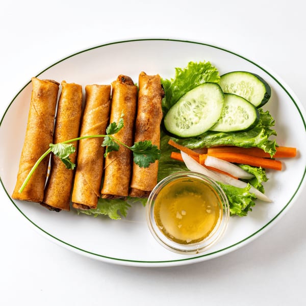 Crispy golden spring rolls with fresh lettuce, cucumber, pickled carrots, daikon, and a dipping sauce.