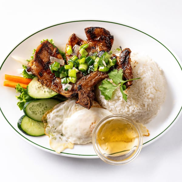 Com Tam, a Vietnamese broken rice dish with grilled pork, fried egg, and vegetables.